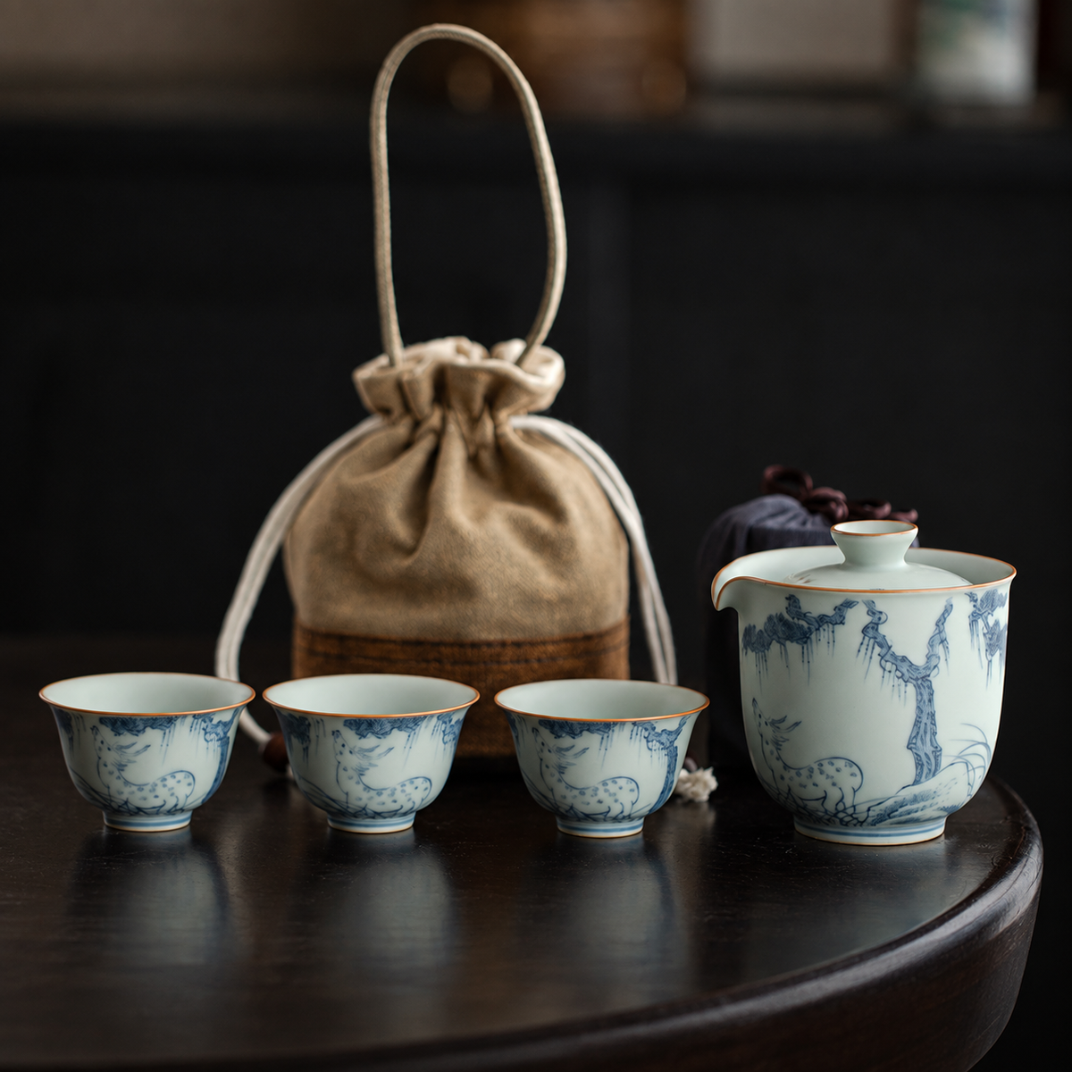 Blue deer and pine painting on a celadon brewer and three cups with matching carrying pouches