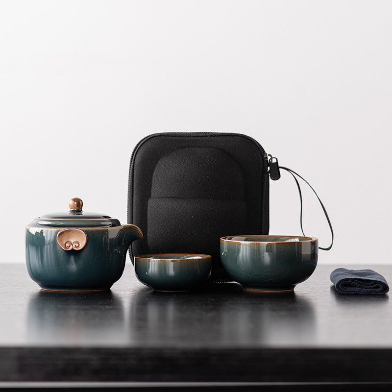 Deep teal ceramic travel teapot with two nesting cups, cloth and black zip case