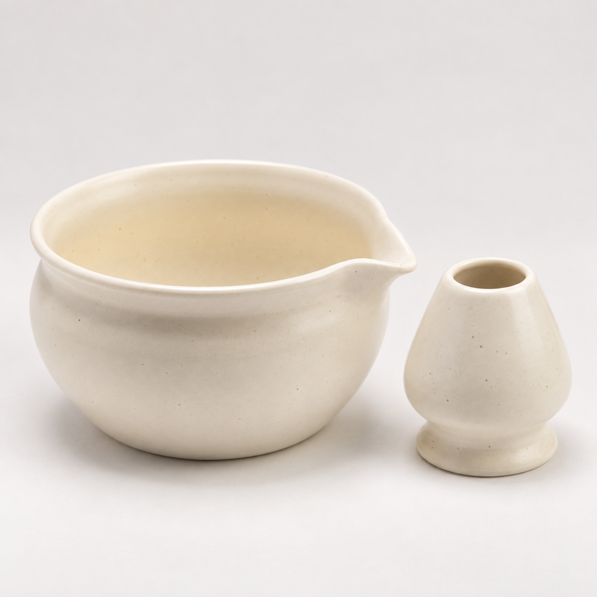 Close-up of the ivory ceramic bowl interior, pouring spout and matching whisk holder