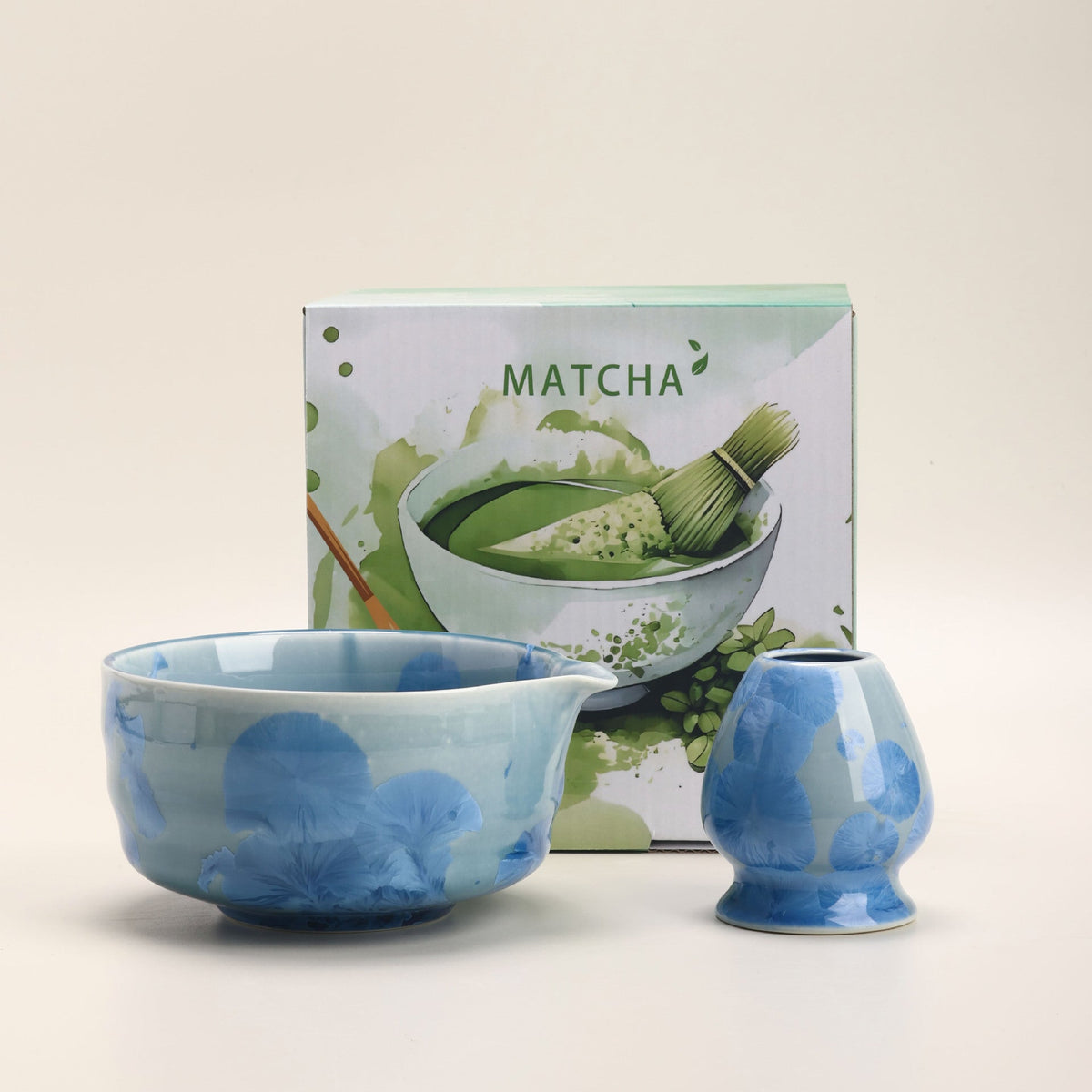 Blue crystalline-glaze ceramic matcha bowl and whisk holder beside their English MATCHA box