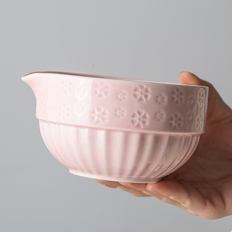 Hand-held pink matcha bowl showing the embossed flowers, fluted base and pouring spout