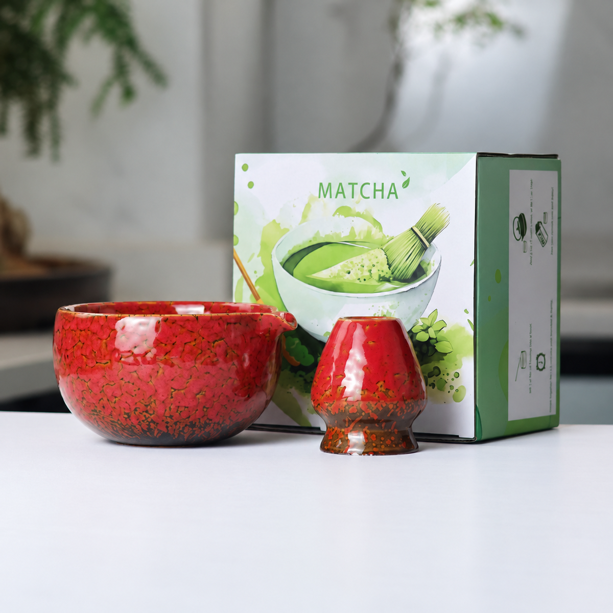 Red mottled reactive-glaze matcha bowl and whisk holder beside the actual English MATCHA box