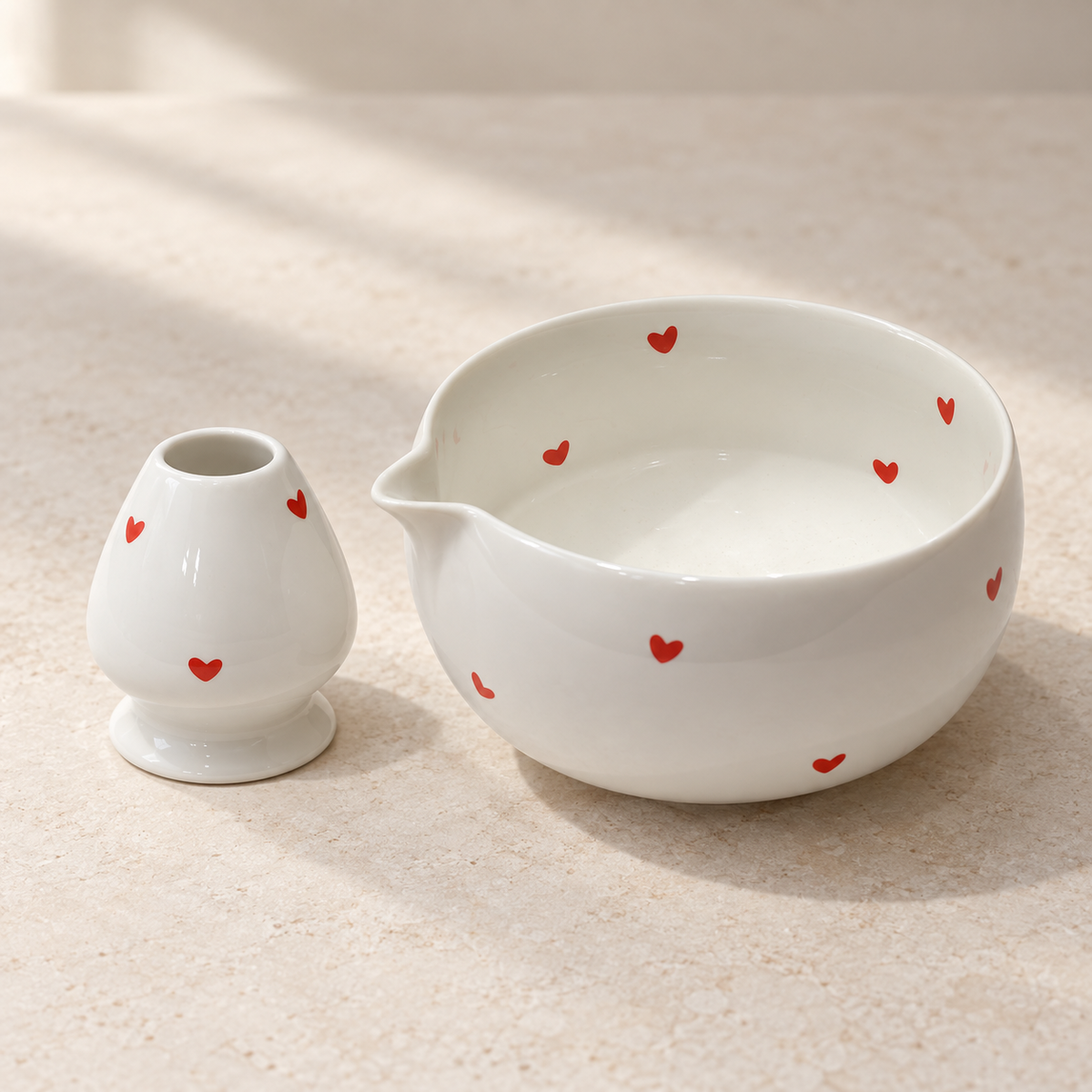 High-angle view of the white ceramic red-heart matcha bowl and matching whisk holder