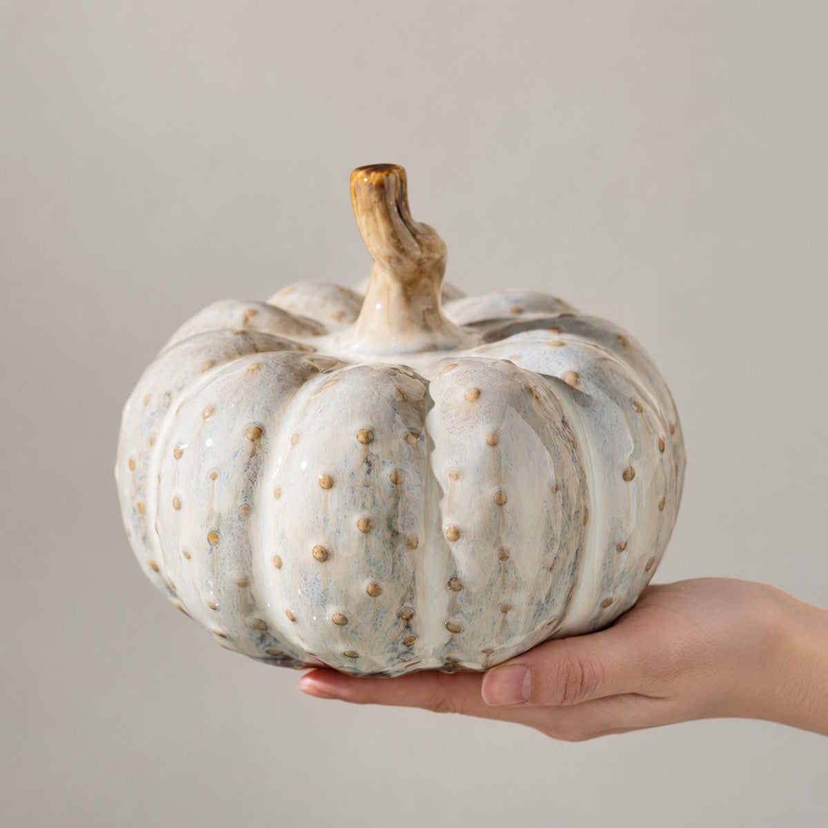 Ceramic pumpkin ornament held in two hands